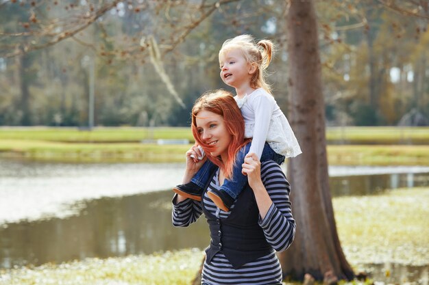 Mother holding daughter in shoulders in a lake