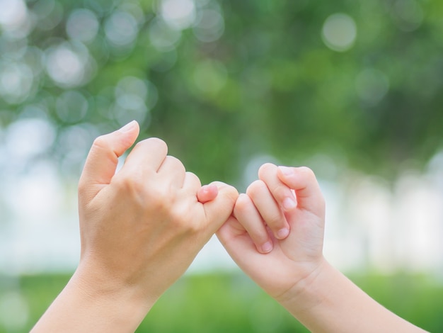 Generi la tenuta della mano del suo bambino in il giorno di primavera all'aperto. concetto di famiglia