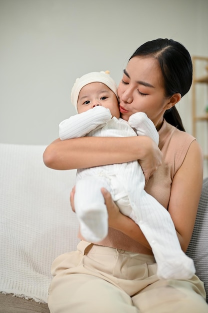 A Mother holding her baby boy while relaxing on the sofa spending time with her son