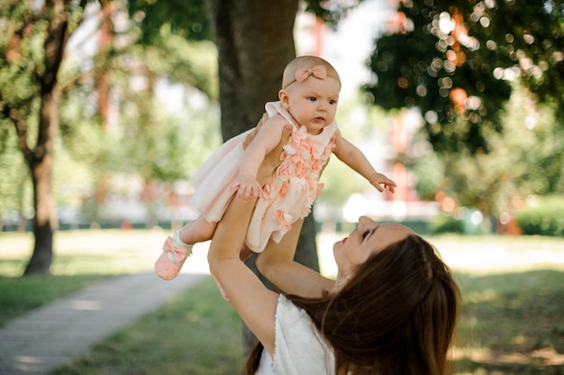 Mother holding her little daughter up in the air in the park