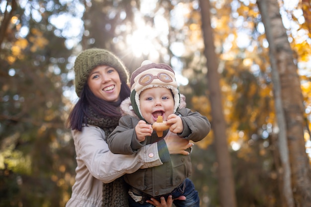 Mother holding her little son in the pilot hat and playing in the toy plane