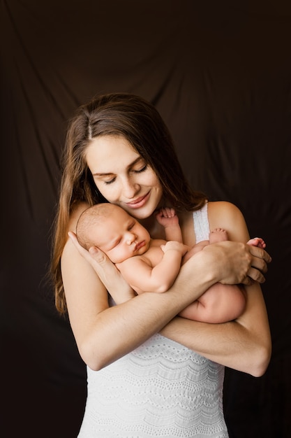 Mother holding her newborn daughter in her arms at a newborn photoshoot