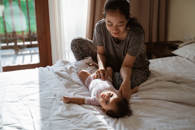 Mother holding a little daughter hands to joke