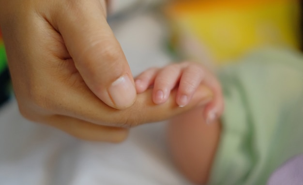 mother holding newborn baby hand