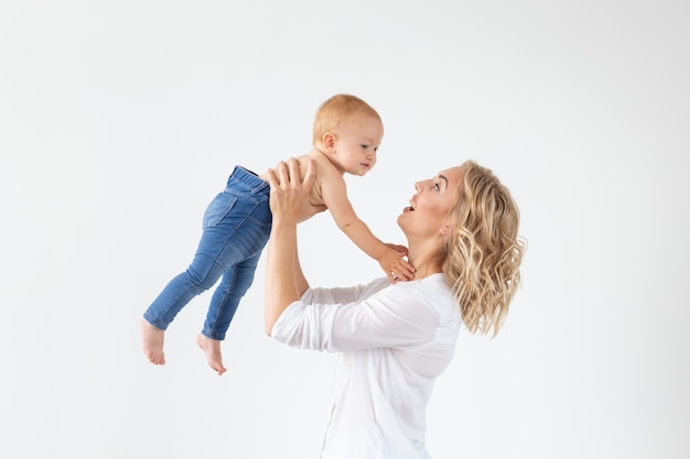 Mother holding sweet baby girl on white wall