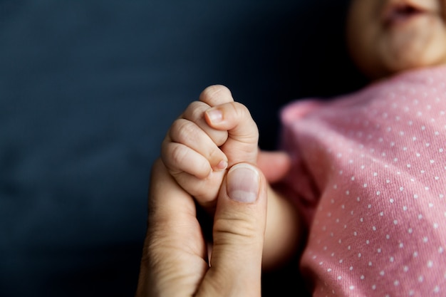 Mother holding tinny newborn fist, family and parents concept 