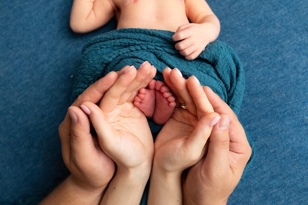 A mother holds a baby's feet while the baby is wrapped in a blue towel