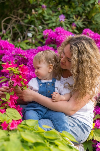 mother holds in her arms a little blond boy with wavy hair Son of the year Floral background