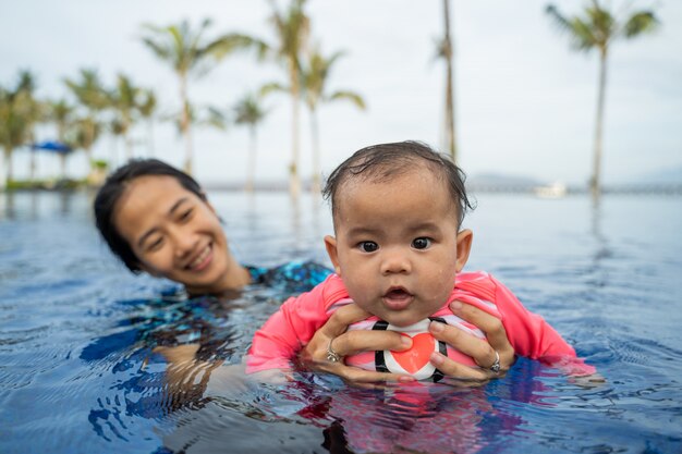 Mother holds her baby while learning to swim