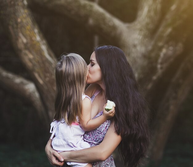 Mother holds her daughter in her arms and kisses