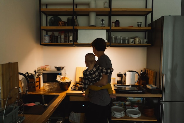 A mother holds her daughter in her arms in the kitchen