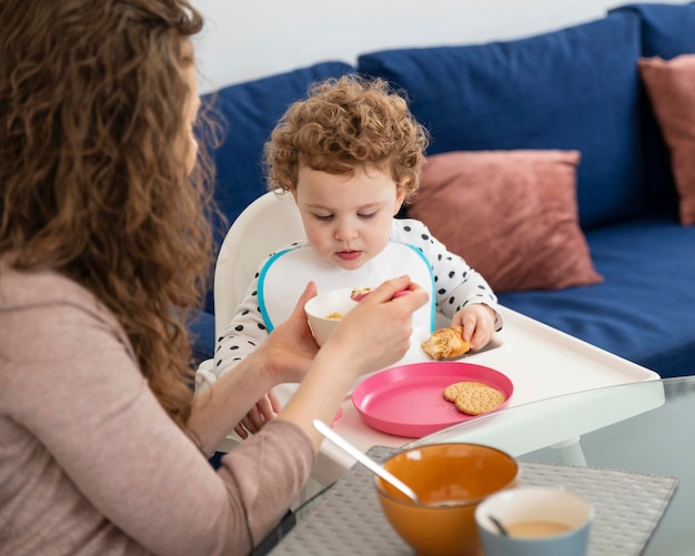 昼食をとっている子供と一緒に家にいる母