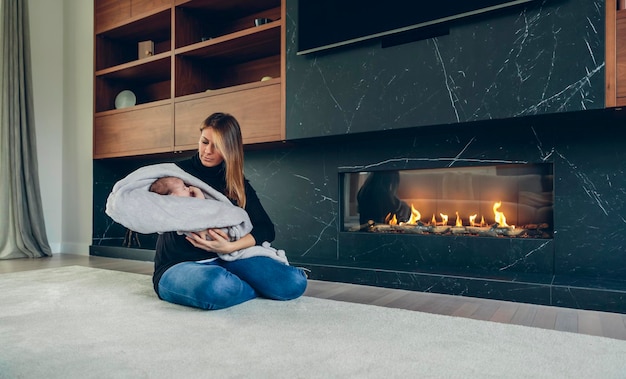 Mother hugging her baby in front of fireplace