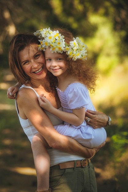 Mother hugging her daughter and holding her in her hands red hair child with mommy in the fields