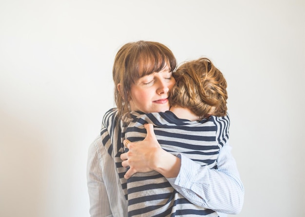 Foto una mamma che abbraccia la figlia, che indossa una camicia a righe.