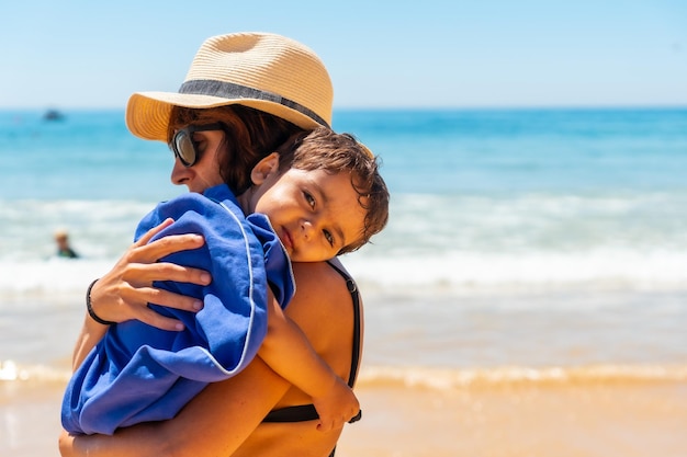 Мать обнимает сына у моря на отдыхе на пляже Алгарве Албуфейра Португалия