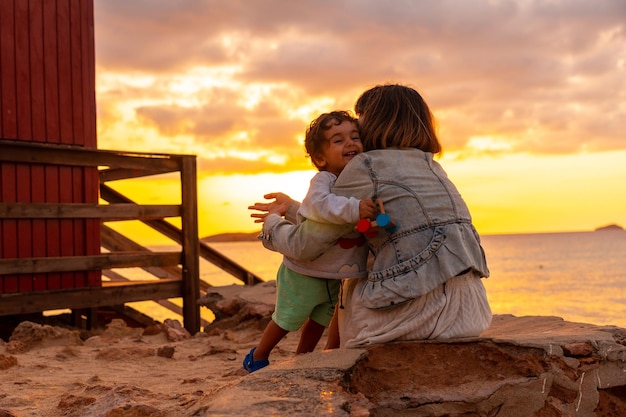 Mother hugging her son at sunset in Cala Comte beach on the island of Ibiza Balearic