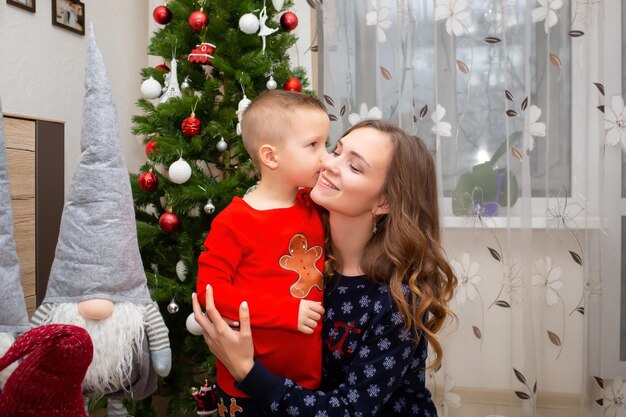 A mother hugs her son at Christmas near the Christmas tree