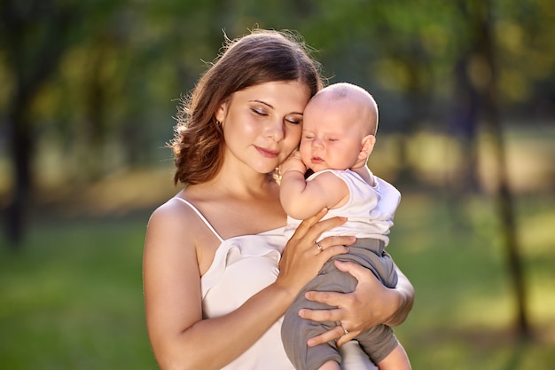 Mother hugs little boy while walking in park