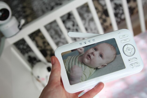 Photo mother is checking the baby monitor for security of the baby