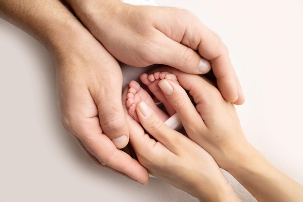 Mother is doing massage on her baby foot Close up baby feet in mother hands on a white background Prevention of flat feet development muscle tone dysplasia Family love care and health concept