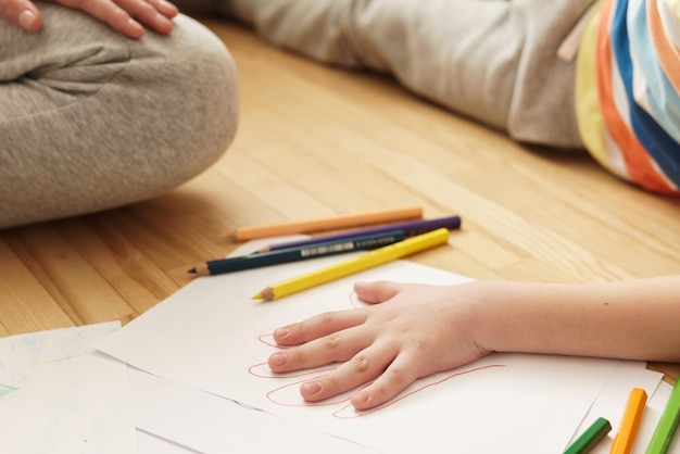 Mother is drawing outline of her son's palm on the sheet of white paper