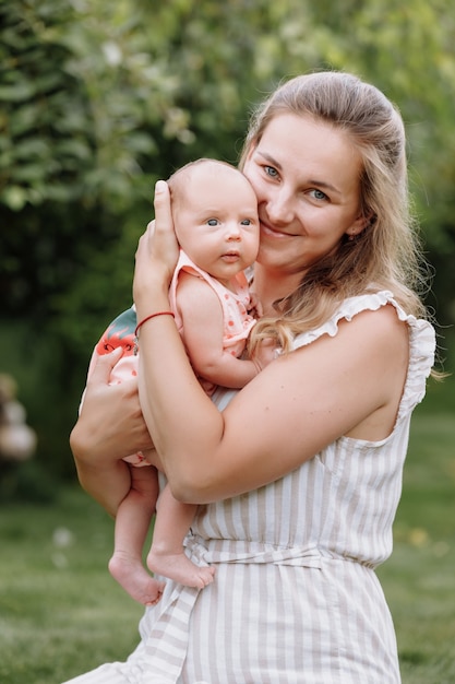 Mother is hugging her baby girl outdoors on summer day