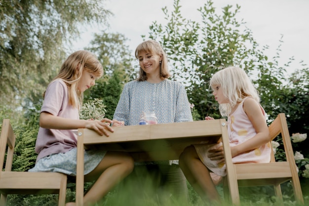 Photo mother is painting with her children in the garden.