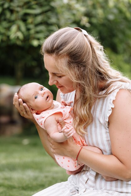 Mother is playing with her baby girl outdoors on summer day