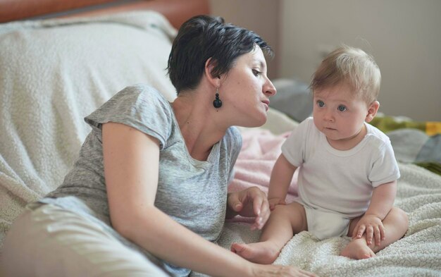 mother is playing with newborn baby at home