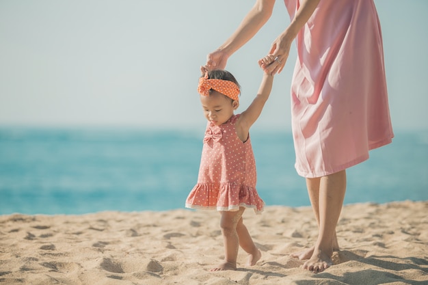 Mother is teaching her daughter walks on the beach