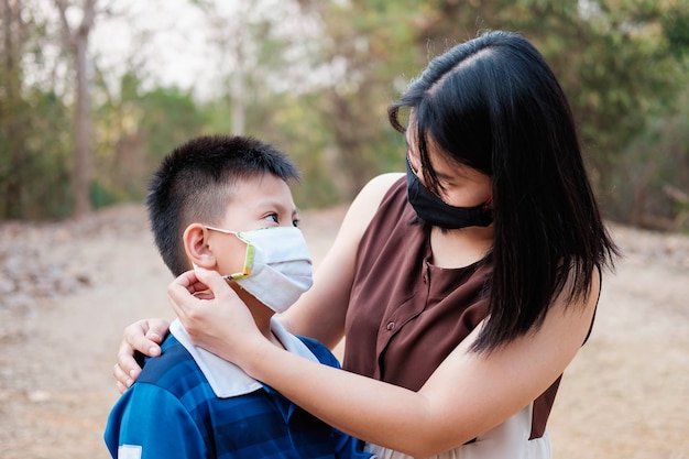 어머니는 covid-19 바이러스로부터 아들을 보호하기 위해 마스크를 쓰고 있습니다.