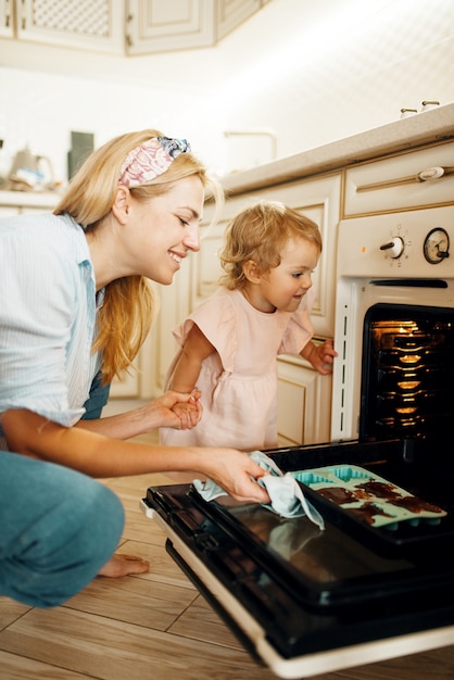 Photo mother and kid remove from the oven baking sheet