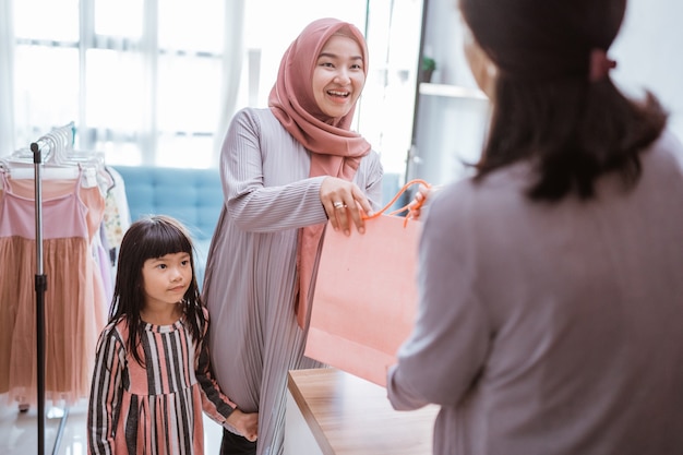 Mother and kid shopping in the mall buying some clothes