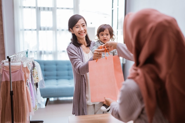 Mother and kid shopping in the mall buying some clothes