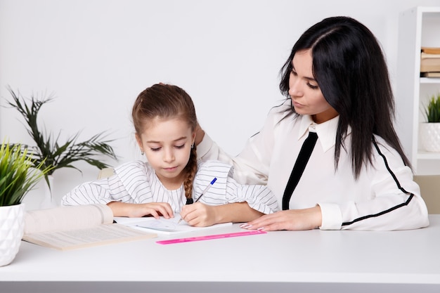 Mother and kid spending time together by sitting and learning.