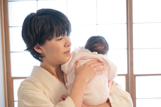 Una madre in kimono che fa ruttare il suo bambino