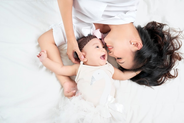 Mother kisses baby lying on the bed closeup