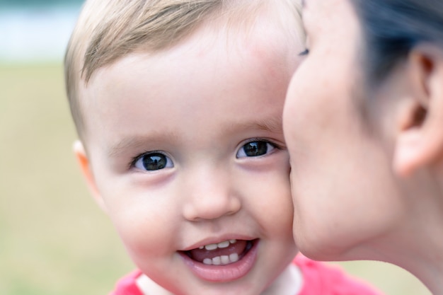 Mother kisses the cheek of a little boy