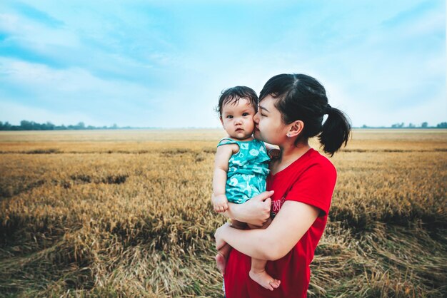 Photo mother kissing baby while standing on field