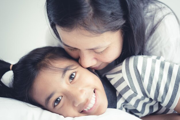 Photo mother kissing daughter on bed