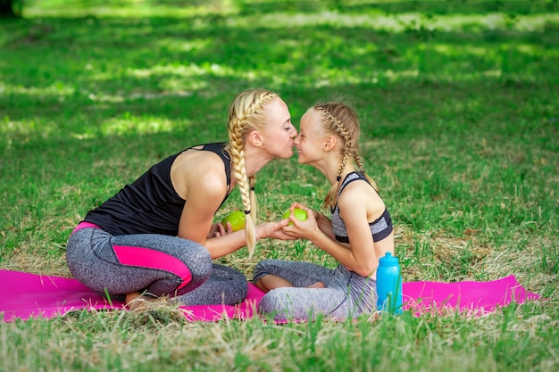 Мать целует нос дочери в парке