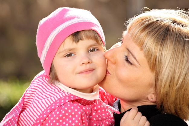 公園で彼女の小さな女の子にキスする母親