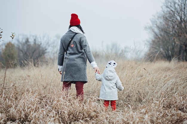 Mother and little baby daughter walking together and having fun in autumn nature background