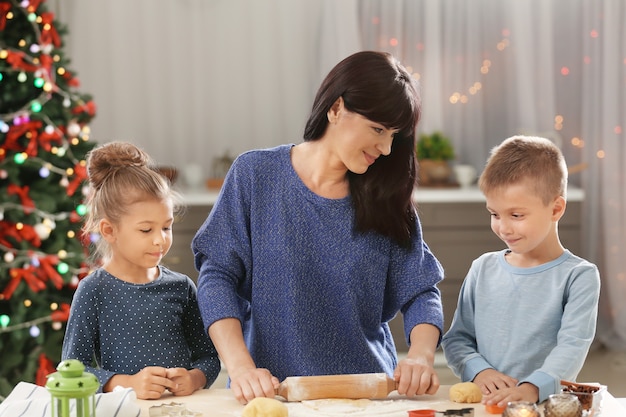 Мать и маленькие дети делают рождественское печенье на кухне