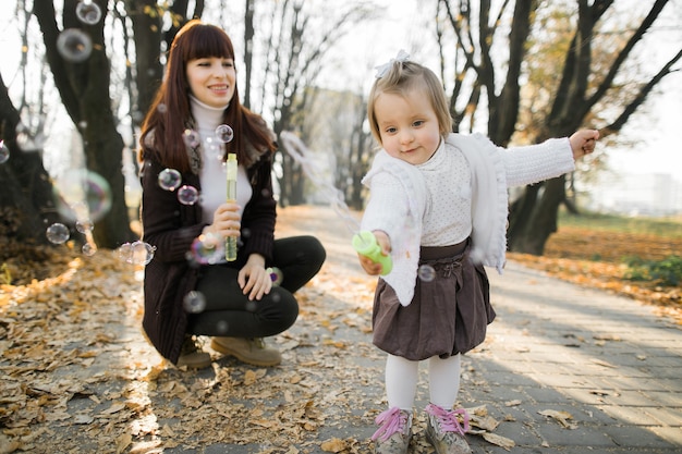 mother and little cute daughter playing together with soap bubbles