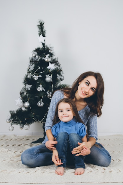 母と幼い娘がクリスマスツリーを飾る