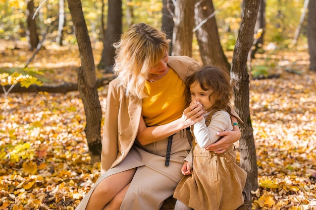 Mother and little daughter enjoying nice autumn day in a park\
season family and children concept