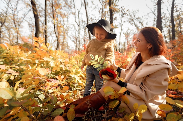 Mother and little daughter girl having fun in autumn