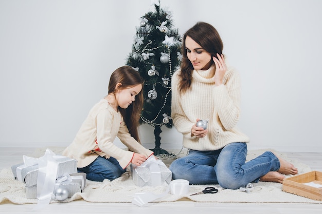 Mother and little daughter pack the gifts 